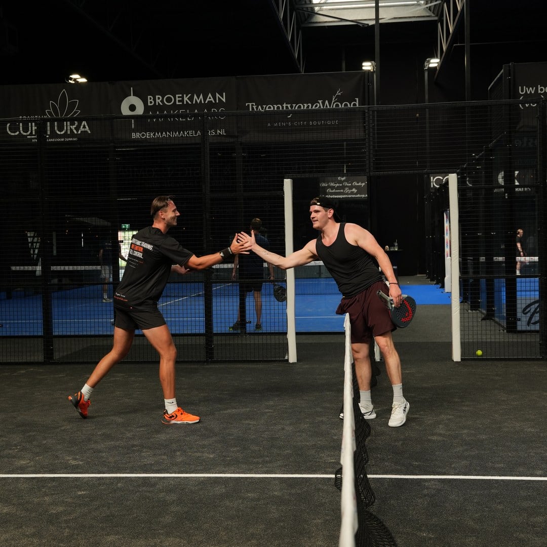 Two founders high-fiving over the net after a match